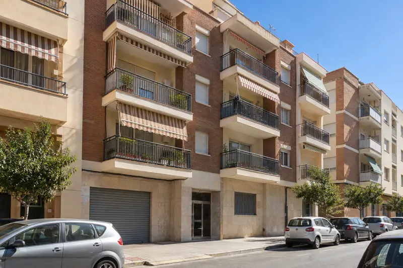Bloque de pisos de ladrillo con balcones y entrada al garaje