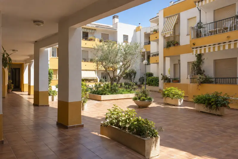 Porche y patio comunitario de un edificio con jardineras