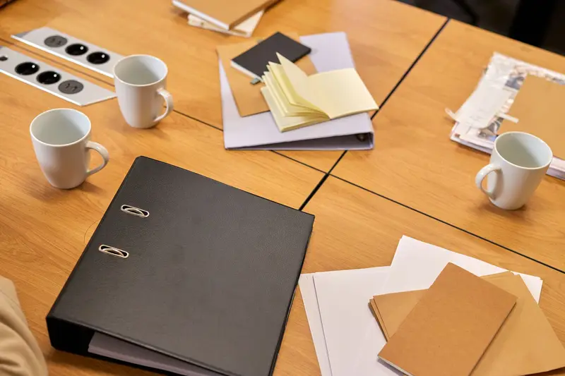 Mesa de trabajo con carpetas, notas y tazas de café