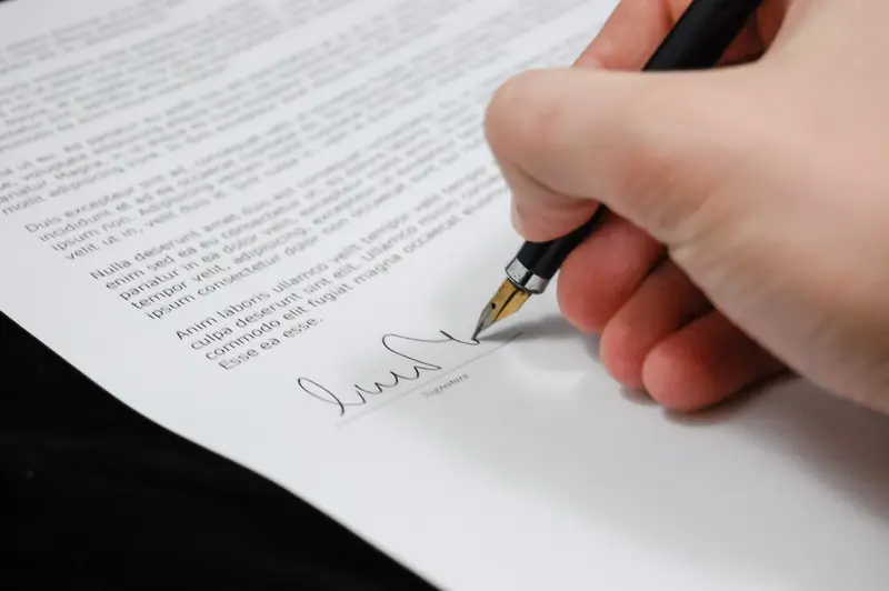 Mano firmando un contrato con una pluma
