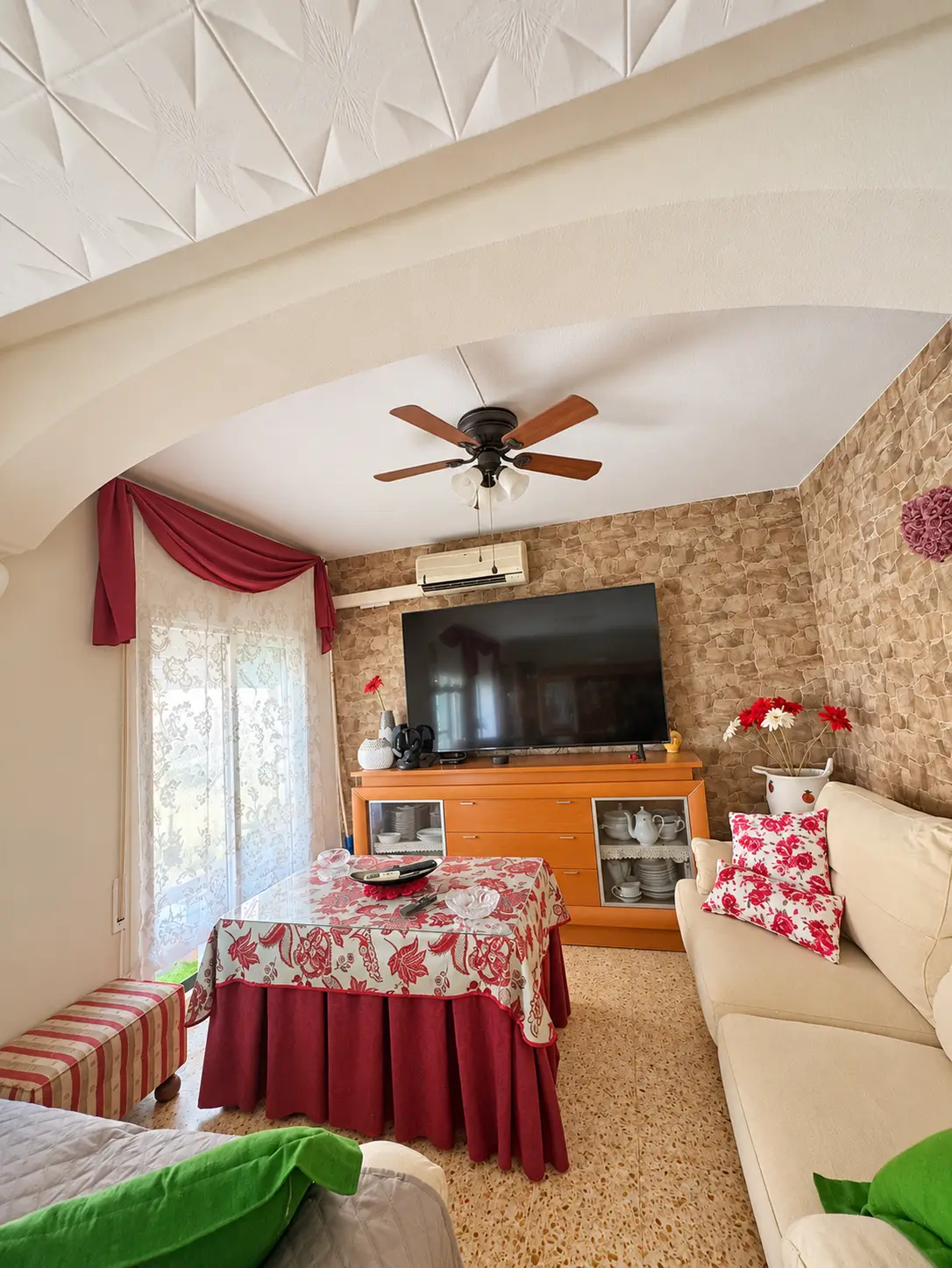 Salón con sofá, televisión, ventilador de techo y aire acondicionado