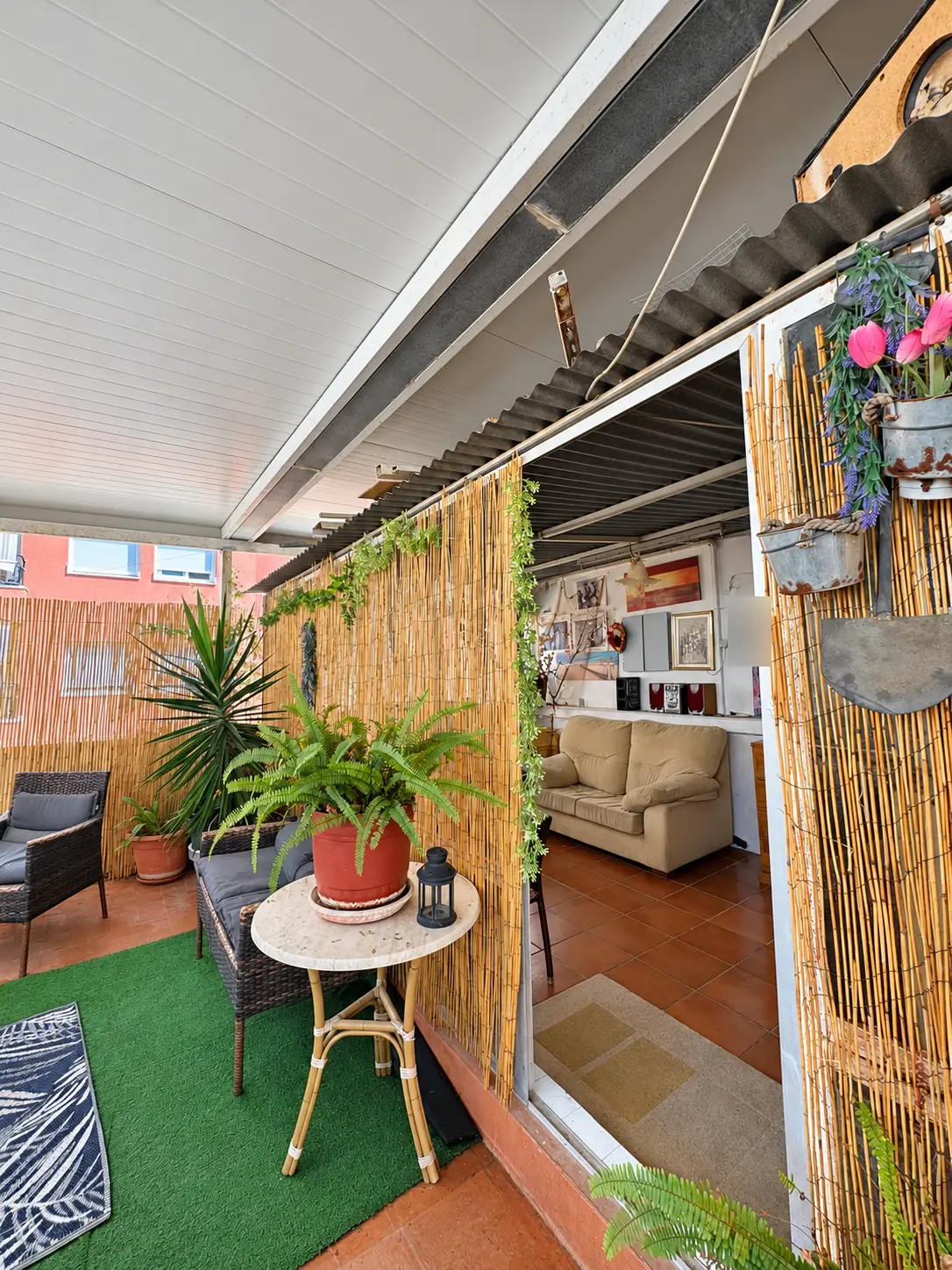 Zona cubierta de la terraza con cañizo, plantas y mesa auxiliar